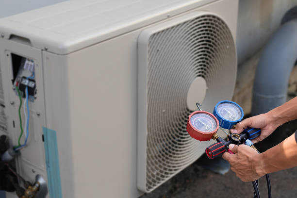 Air conditioning, HVAC service technician using gauges to check refrigerant and add refrigerant.