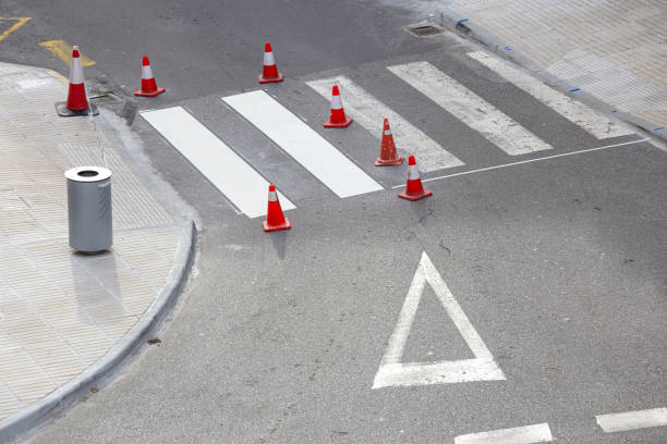 Road painting maintenance concept. Painting white street lines on pedestrian crossing and road cones on city. No people