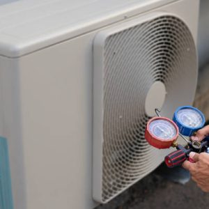Air conditioning, HVAC service technician using gauges to check refrigerant and add refrigerant.